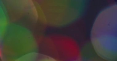 Bokeh ışığı. Lens fişeği. Odaklanmamış yeşil turuncu neon renkli gökkuşağı deseni soyut arka planda parıldıyor.