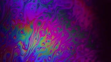 Holografik sıvı. Odaklanmamış boya suyu. Parlak sıvı damlaları renkli bulanık dokular yayar. Neon gökkuşağı ıslak ışık arkaplanı.