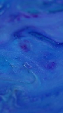 Dikey video. Mavi dokuya sıçra. Arkaplanı boya. Akan akrilik soyutlama üzerinde yüzen parlak renkli su damlası..