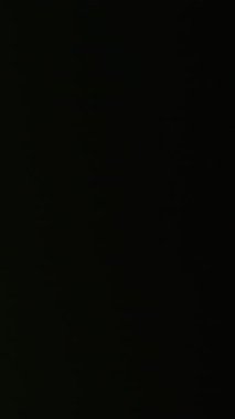 Dikey video. Odaklanamayan ışık lensi. Film parıltısı. Renkli eski parlaklık optik etkisi. Sanat yeşili gece soyut ışın siyah arkaplanı.