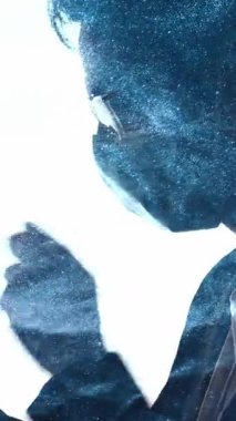 Dikey video. Toz kirliliği. Hava kirliliği. Mavi parçacıklar yüzüyor. Yüzünde maske olan hasta bir adamın silueti. Telefonları beyazın üzerinde izole edilmiş..