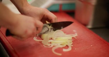 Soğan doğruyorum. Sebze dilimliyorum. Şef profesyonelce kırmızı pano restoranının mutfağında çiğ beyaz baharatlı malzemeyi bıçakla kesiyor..