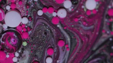 Damla karışımı. Akrilik boyalı su. Bulanık pembe mor renk yağ soyut yaratıcı arka planda parlak lekeler süzülüyor.