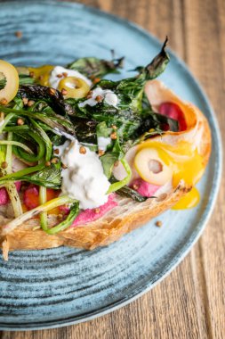 Sandviç tabağı. Lezzetli yemek. Üstünde yeşil ızgara sebzeler ve bruschetta üzerine doğranmış zeytin pancar püresi olan renkli bir tost..