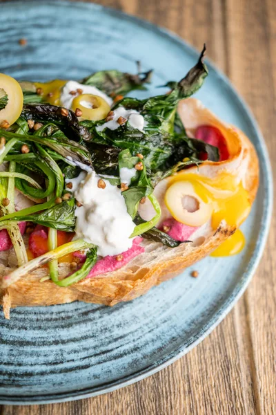 Sandviç tabağı. Lezzetli yemek. Üstünde yeşil ızgara sebzeler ve bruschetta üzerine doğranmış zeytin pancar püresi olan renkli bir tost..