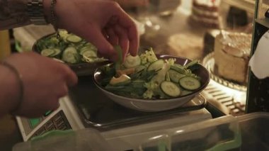 Vejetaryen mutfağı. Salata hazırlıyorum. Şefin eli porsiyonlu yemek için salatalık yeşili avokado ekliyor. Yemek ağırlığı profesyonel aygıt.