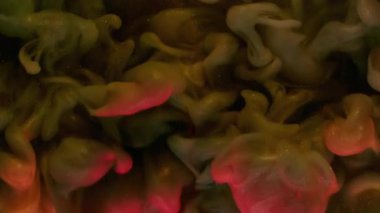 Akrilik mürekkep dumanı. Soyut sim sisi. Odaklanmamış turuncu pembe renkli bulut parçacıkları gökkuşağı resimleri koyu siyah arka planda yayılıyor..