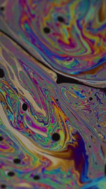 Dikey video. Yağ damlası. Mürekkep karışımı. Odaklanmamış yeşil mavi renk pembe mor yuvarlak doku soyut koyu siyah arkaplan üzerinde yüzüyor.