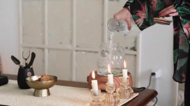 Su akıyor. Çay seremonisi. Kadın elleri cam çaydanlığı ferahlatıcı, sağlıklı yaşam tarzıyla dolduruyor. İçerde huzur dolu mumlar yakıyor..