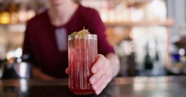 Barmen işi. İçecek yapıyorum. İşçi, kırmızı buzlu uzun bardağa saman ekliyor. Meyhane masasında aromalı nane şekeri soğuk kokteyli..