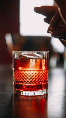 İçkiyi hazırlıyorum. Citrus kokteyli. Barmen el geniş bardakta negroni servis ederek portakal suyu serpiyor. Aromatik buzlu içecek..