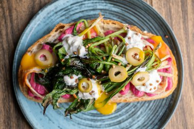 İştah açıcı öğle yemeği. Porsiyon tabağı. Tabakta canlı malzemelerle servis edilen sandviç. Yeşil ızgara yapraklı yemek pancar kökü zeytin sarısı sosu.