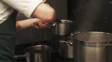 Çorba hazırlanıyor. Yiyecek dolduruyorum. Büyük metal tavadan sıcak yemeğin kepçe porsiyonu. Mutfak elektrikli sobası için profesyonel yemek takımı..