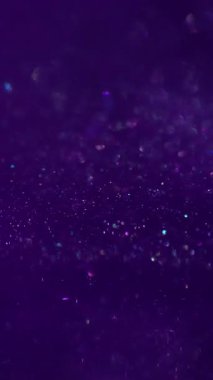 Dikey video. Parıldayan sıvı. Menekşe rengi. Renkli peri mürekkebi parlak sanat suyu akışını kaplıyor. Odaklanmamış doku parlayan parçacıklar soyut arkaplanı harmanlıyor.