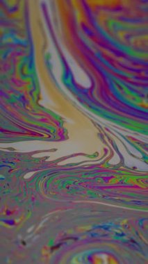 Dikey video. Damla dokusu. Benzin sızıntısı. Soyut sanat arka planında yüzen mavi boya baloncukları akarken odaksız yeşil mor renk..