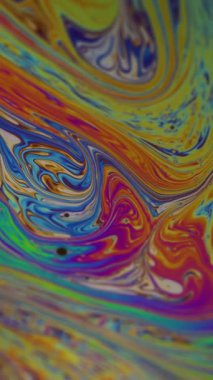 Dikey video. Boya karışımı. Su yakıtı. Odaklanamayan sarı mor renkli mürekkep soyut akrilik arka planda mavi lekeler sızdırıyor..