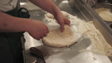 Para kazanmak. Pizza pişirme. Yetenekli aşçı eli, metal masada dönen buğday tabanı fırlatıyor. İtalyan geleneksel mutfak restoranı.