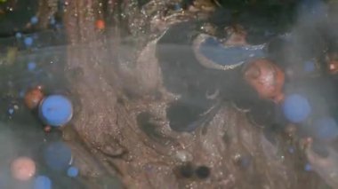 Dye oil. Bubble liquid. Defocused blue orange purple colorful ink round glitter vapor texture floating on art acrylic abstraction.