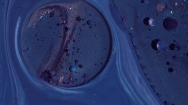 Boya dökülmüş. Mürekkep sanatı. Odaklanmamış mor renkli, parlak yağ kabarcıkları soyut arkaplanda yüzen akrilik sıvı pigmenti etrafında parıldıyor.