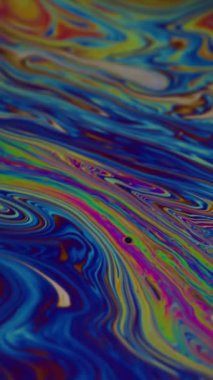 Dikey video. Boya damlası. Lekeli sanat. Soyut akrilik yeşil zemin üzerinde yüzen mavi mor renkli damlacık yağı dokusu.