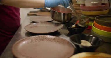 Yemek kepçesi. Porsiyonlu yemek. Şef sıcak kırmızı sıvıyı kaselere dolduruyor. Mutfak masasında borç servisi yapıyor..