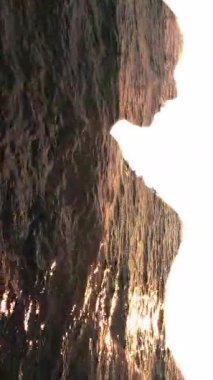 Dikey video. Su silueti. Doğa enerjisi. İç huzuru. Rahatlamış kadın profilinde çift pozlu gün batımı dalgaları beyaz üzerine izole edilmiş..