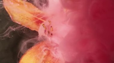 Mürekkep dalgası. Renk sıçraması. Odaklanmamış turuncu zambak doğası. Soyut koyu siyah arka planda kimyasal suya pembe duman boyası..