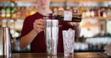 Karışık içecek. Barmen sayacı. Adam profesyonelce jigger ile şurup ekliyor. Soğuk buz küpleri kokteyl için hazırlanıyor..