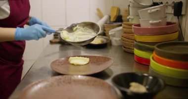 Aşçılık işi. Ezilmiş patates servis ediyorum. Eldivenli şef büyük tabağa yumuşak sebze yemeği koyuyor. Restoran mutfağının siparişi hazırlanıyor..