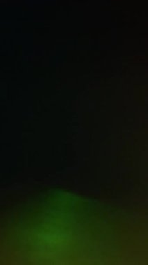 Dikey video. Işık sızıntısı. Düşük bulanıklık yansıması. Koyu arkaplanda parlayan renkli odaklanmış kiriş. Gece ışını soyut kırılma efektini örtüyor.