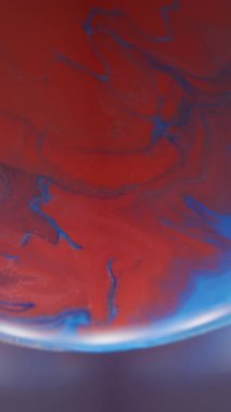 Dikey video. Sanat sıvısı. Bulanık boya karışımı. Kırmızı mavi emülsiyon mercek ışığına karışıyor. Odaklanamayan renk arkaplanı üzerindeki girdap akışı.