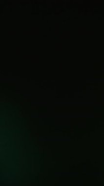 Dikey video. Lens fişeği. Odaklanamayan parıltı. Soyut koyu renkli siyah arkaplanda mistik bir ışık parlaması. Nostaljik film ışını yansıma sanat efekti.