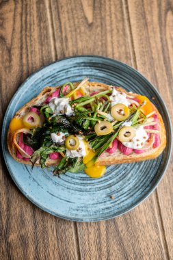 Sandviç tabağı. Lezzetli yemek. Üstünde yeşil sebzeler olan renkli bir tost. Pancar püresi ile doğranmış zeytin ve bruschetta..