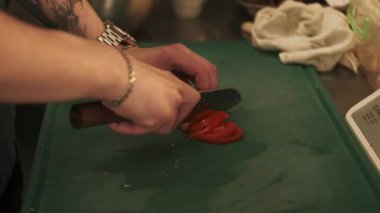 Salata hazırlıyorum. Vejetaryen mutfağı. Şef mutfak masasında taze domates dilimliyor. Malzemeleri profesyonel ölçeklendirme tabağına yerleştiriyorum..