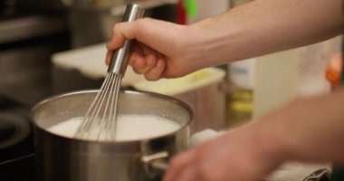 Aşçılık işi. Süt çırpıyorum. Şef ocakta metal tencerede kaynamış beyaz köpüklü tatlı çırpıyor. El yapımı krema sosu..