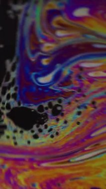 Dikey video. Damlacık yağı. Renk karışımı. Odaklanamayan sarı mor mavi mürekkep su dokusu akan yeşil yuvarlak lekeler soyut sanat arka planına dökülüyor.