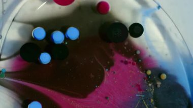 Jel boya. Mürekkep karışımı. Odaklanamayan mavi kırmızı renk su kabarcıkları etrafında yağ lekesi soyut arka planda siyah emülsiyon sızıntısı oluşturur..