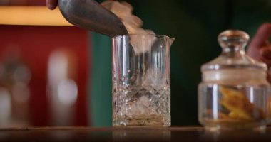 Buzları eritmek. Kokteyl yapımı. Barmen el, uzun bardaktaki donmuş küp malzemelerle profesyonel aletleri karıştırıyor. Serinletici içecek için soğutma.