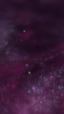 Dikey video. Parıltılı boya. Toz sıvısı. Mor parçacıklar suda parlak pigmentler oluşturur. Parlak soyut bulanık bulut patlaması siyah arkaplan.