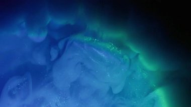 Mürekkep sisi. Gökkuşağı bulutu sıçraması. Bulanık mavi renkli parıltılı su ışıltılı buhar soyut siyah sanat arka planına yayılıyor.