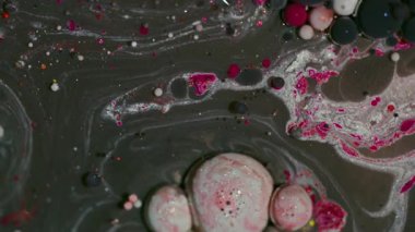 Boya dökülmüş. Mürekkep sanatı. Bulanık pembe, kırmızı, parlak yağ kabarcıkları soyut arkaplanda yüzen akrilik sıvı pigmentler etrafında parıldıyor..