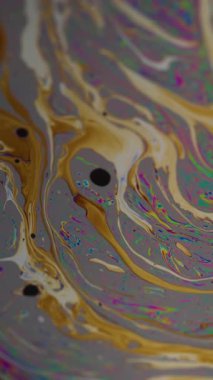 Dikey video. Yağ sıvısı. Boya lekeleri. Odaklanmamış turuncu mavi renk ıslak baloncuk deseni soyut mor arkaplan üzerinde yüzüyor.