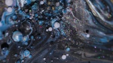 Su karışımı dök. Boya sıvısı. Odaklanmamış mavi bronz altın rengi ışıl ışıl beyaz parçacıklar yağ kabarcıkları soyut arkaplanda akıyor.