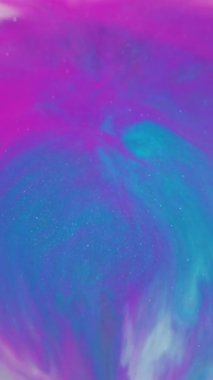 Dikey video. Boya patlaması. Bulanık boya karışımı. Yuvarlak renkli pigment damlası akrilik sıvıda dökülmüş. Pembe beyaz mavi parıldayan akış soyut arkaplan.