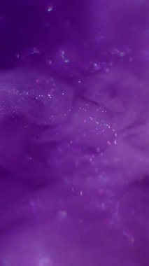 Dikey video. Işıldayan sıvı. Mürekkep dalgası. Mor menekşe metalik toz sanat sisi suyu. Odaklanmamış parlak akış sıçrama renk soyut arkaplan.