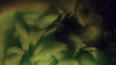 Parlak mürekkep patlaması. Sis bulutu. Odaklanamayan yeşil renk, parıldayan su gökkuşağı deseni akrilik koyu siyah sanat soyutlamasına yayılıyor..