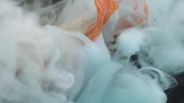 Dikey video. Renkli çiçek patlaması. Boya sıvısını karıştır. Odaklanmamış mavi turuncu duman dumanı. Soyut sanat üzerine zambak bitkisi. Karanlık arka plan..