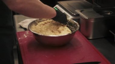Hamur yoğurmak. El yapımı hamur işi. Eldivenli fırıncı, profesyonel mutfakta elektronik pulların yanında metal kasede malzemeleri karıştırıyor..