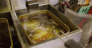 Kızartma. Mutfak malzemeleri. Profesyonel sanayi ısıtıcı mutfak yağ kızartma makinesi. Pişirmek için paslanmaz çelik konteynır septi.