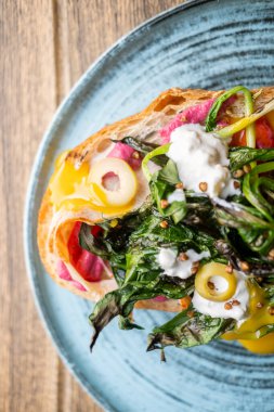 Kahvaltı servis edildi. Lezzetli bruschetta. Sağlıklı vejetaryen tostu ve pancar otları. Ekmeğin üstünde ızgara yeşillikle sulu kremalı sos..